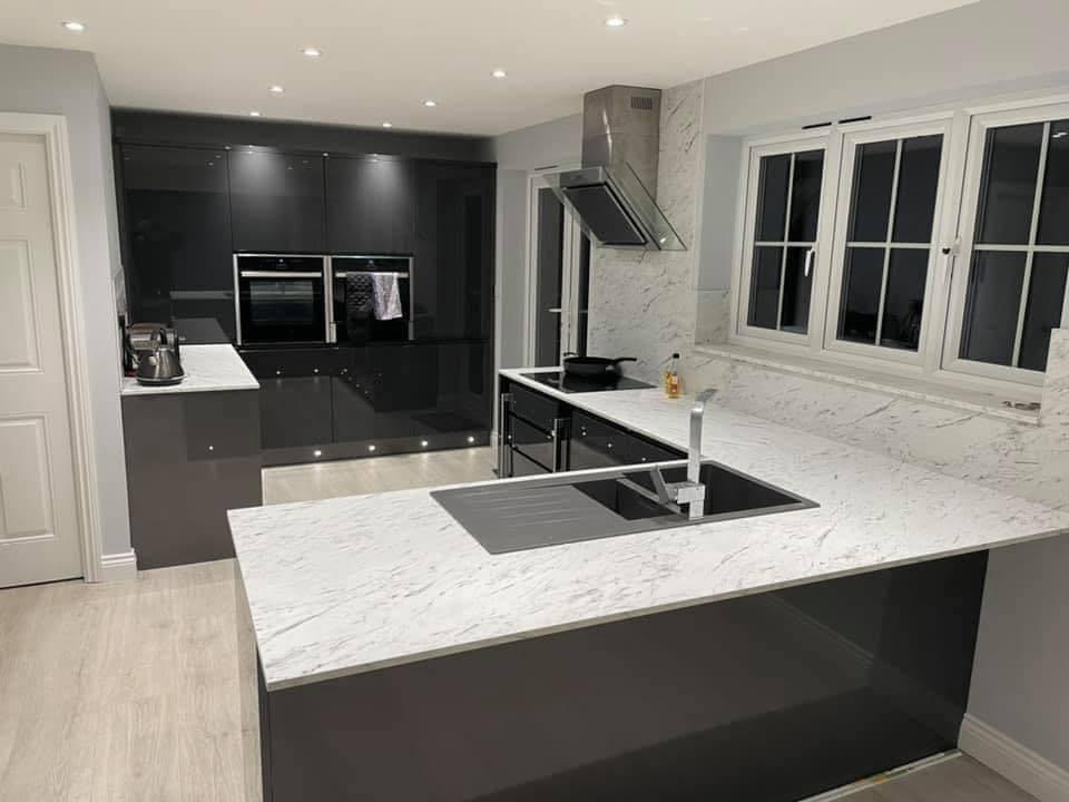 Wide view of a dark grey gloss kitchen with a marble-effect peninsula