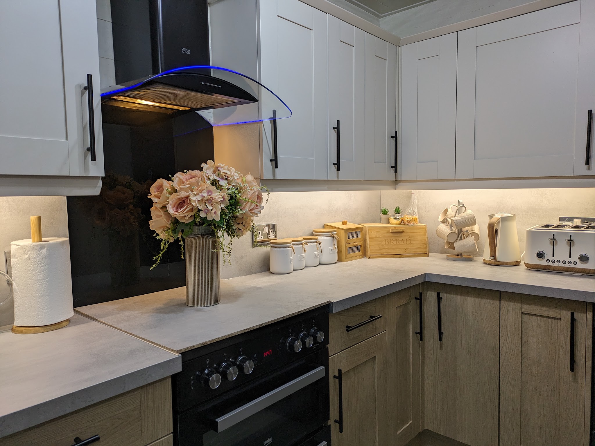White shaker wall units over oak-effect base units with a black range cooker
