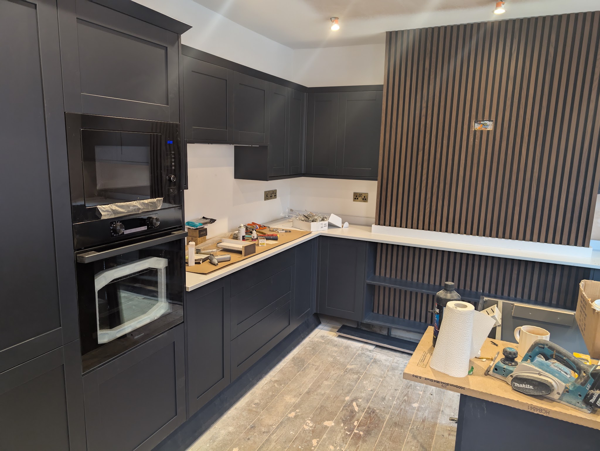 Navy kitchen part way through fitting, with tools on the worktop