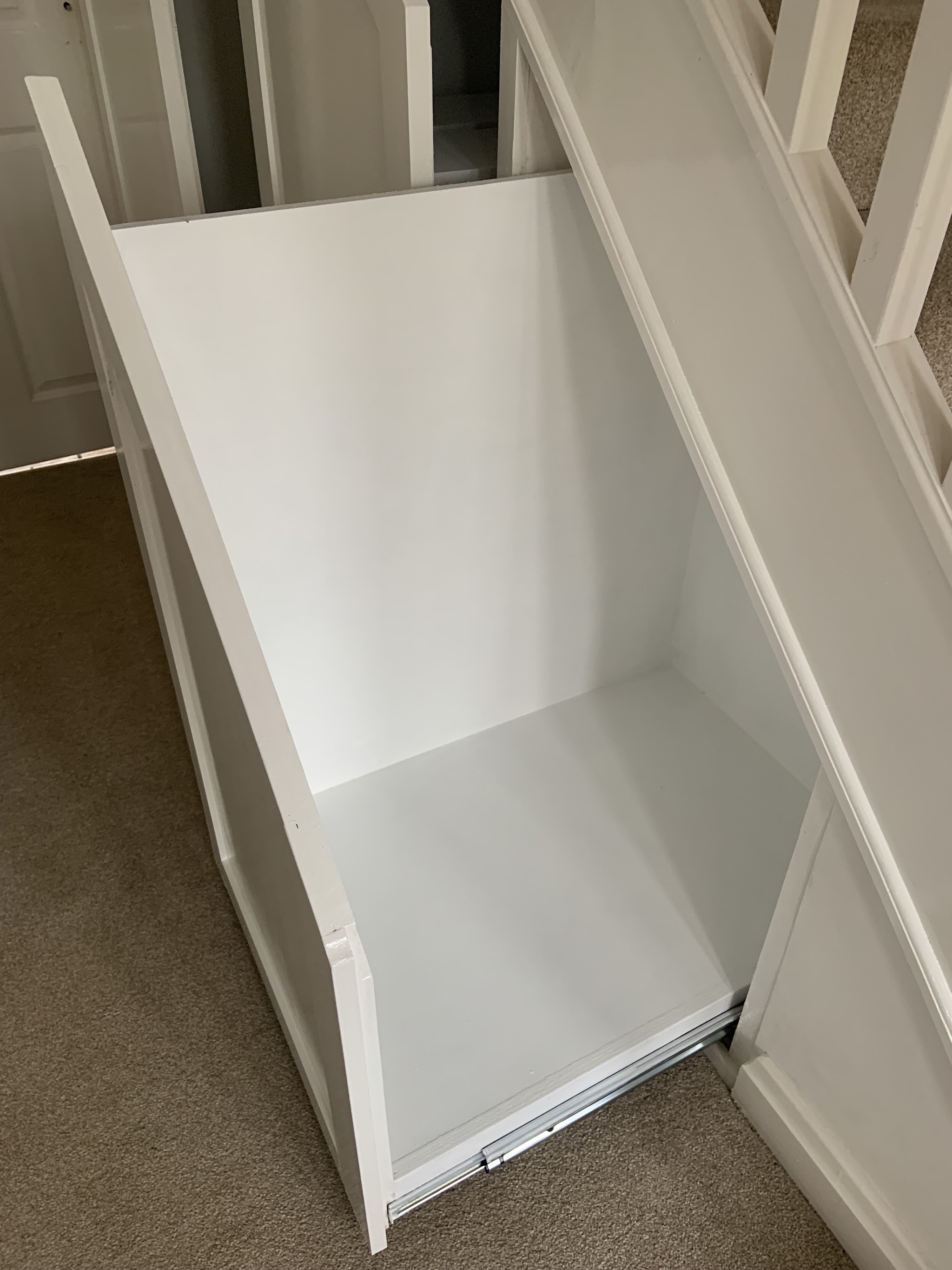 Bespoke white pull-out cupboard built into the space under a staircase