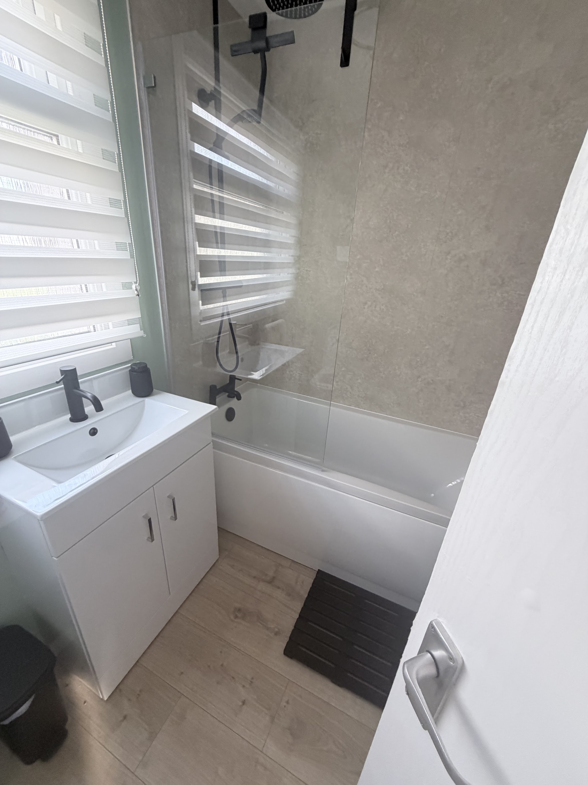 Renovated bathroom with a white vanity unit and stone-effect wall panels