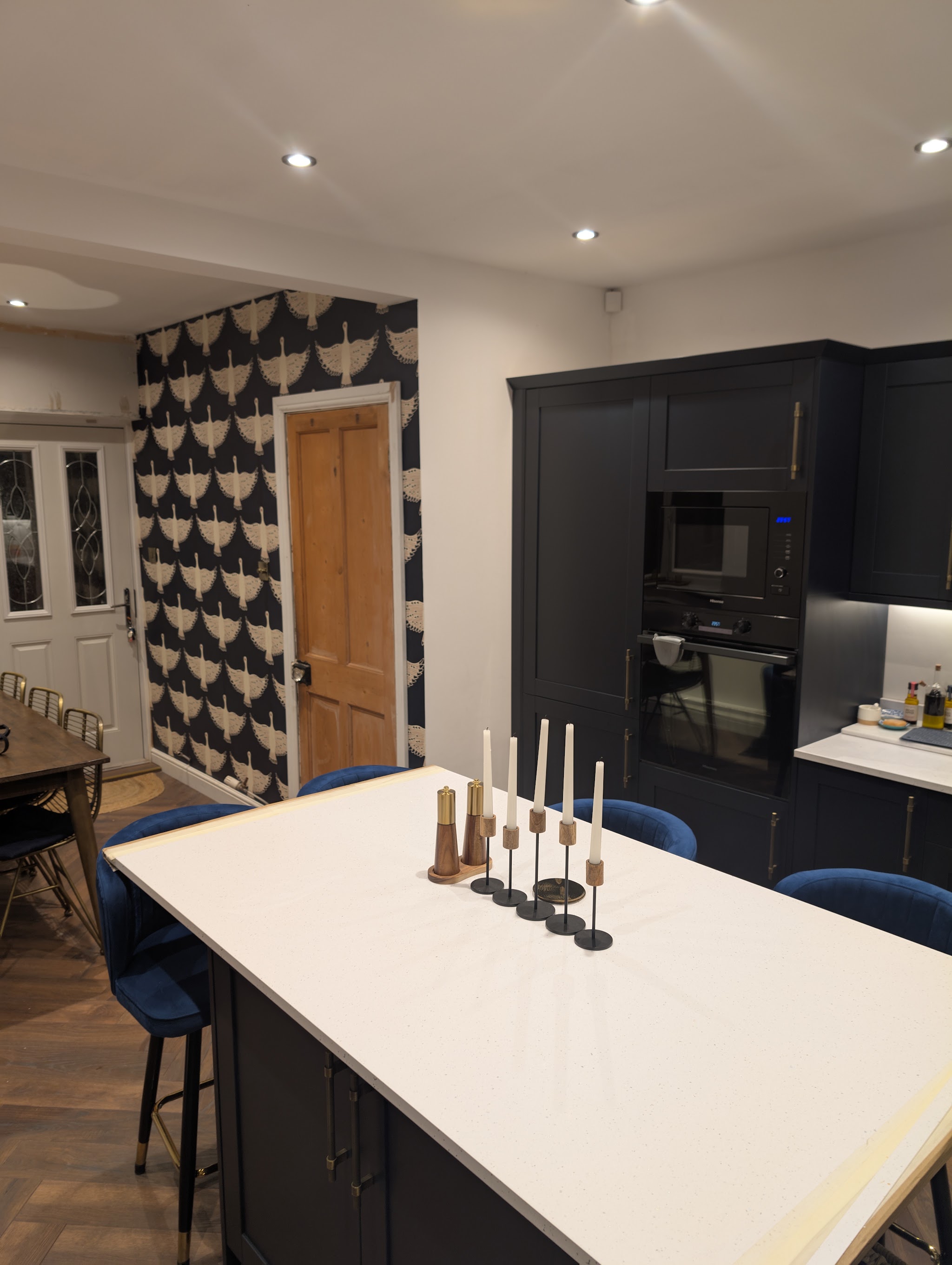 Navy shaker kitchen with a white-topped island and statement wallpaper